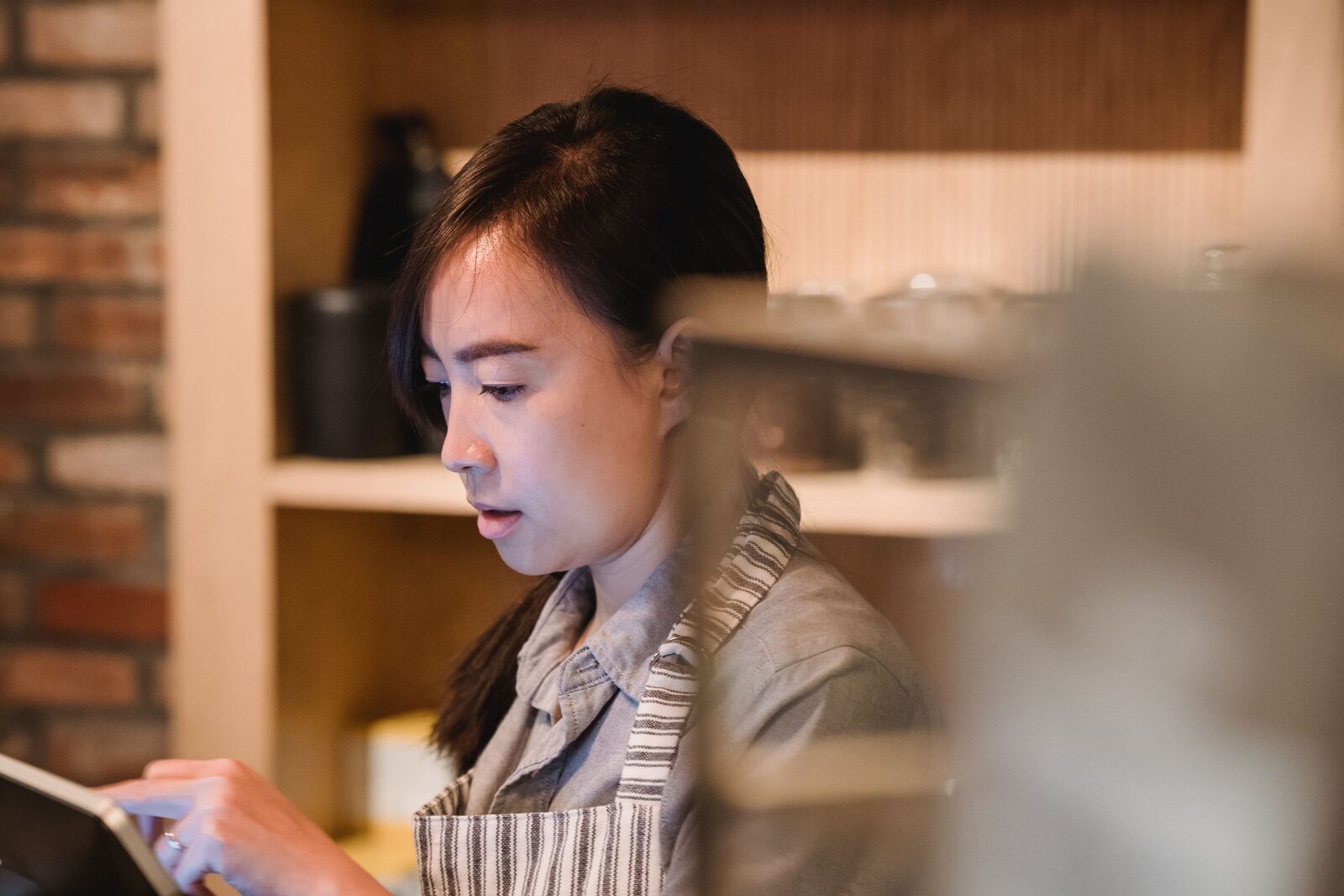 Nhân viên quán xem thiết bị quản lý thẻ thành viên tại quầy thu ngân