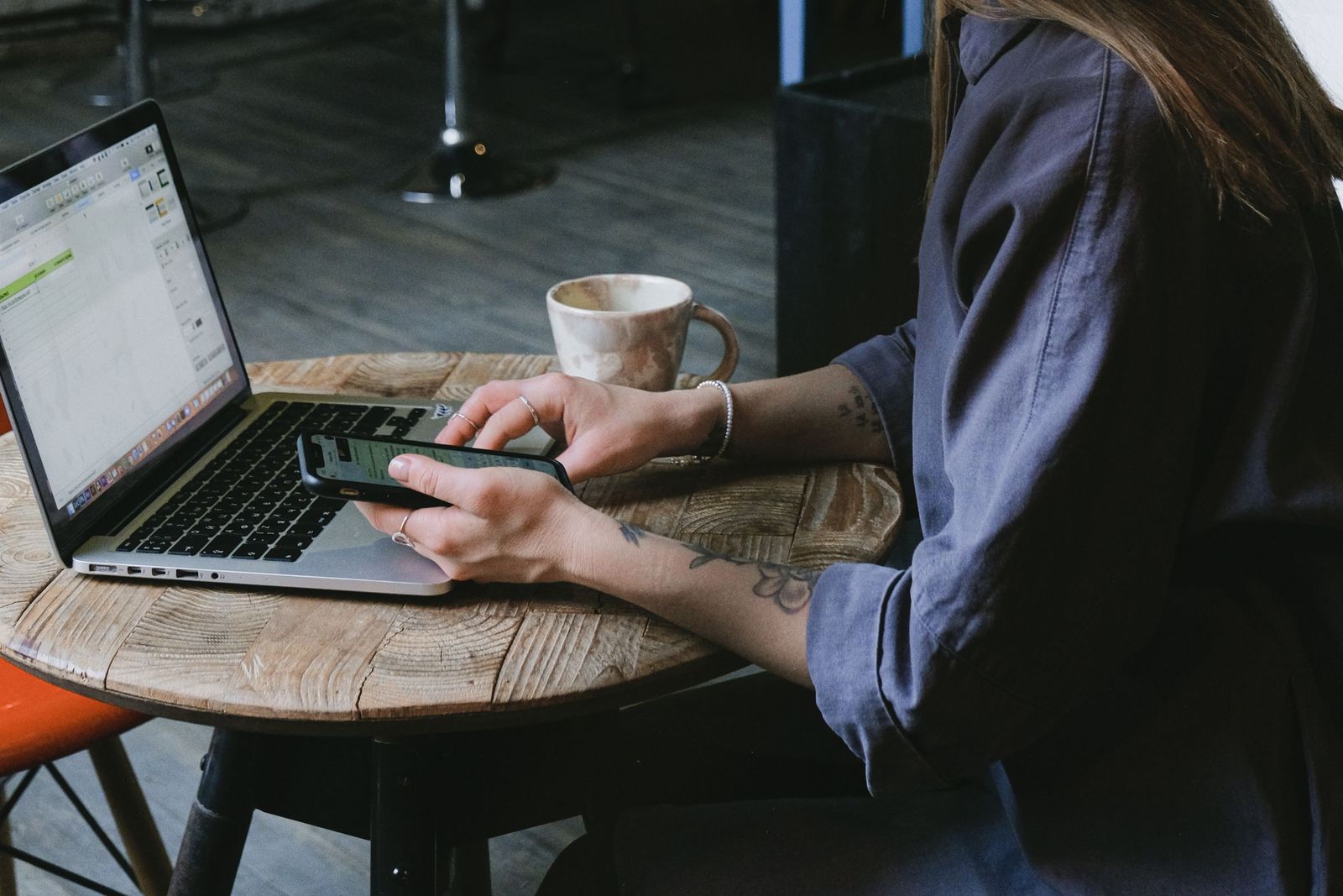 Chủ quán chỉnh mẫu thẻ trên laptop, điện thoại xem trước trong tay